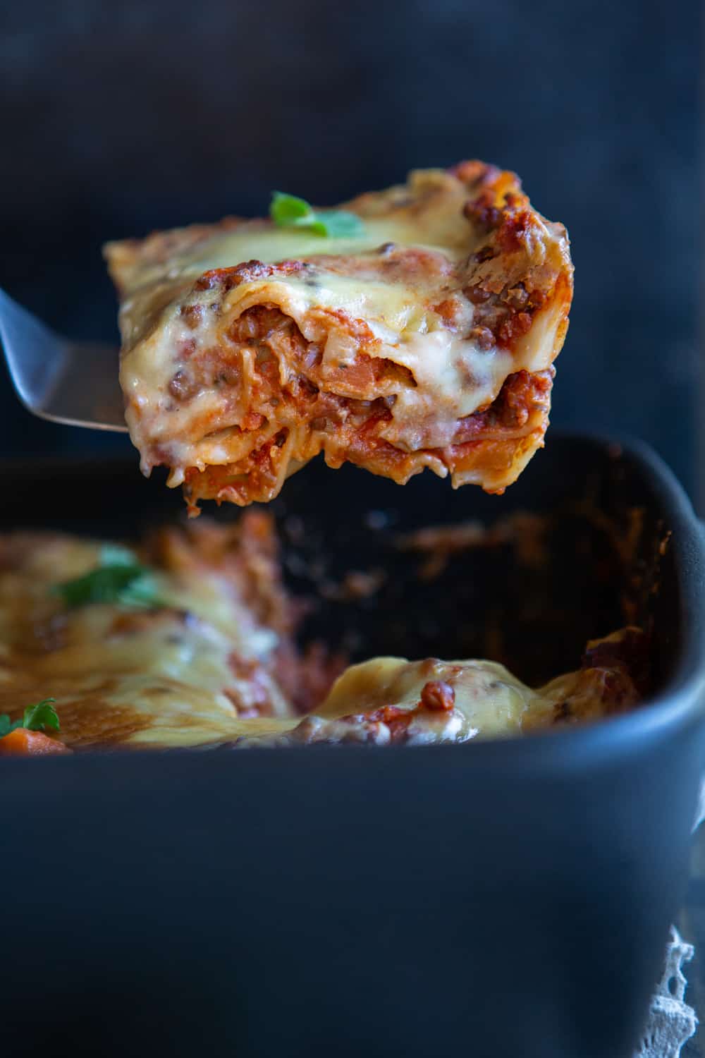 Slice of lasagna lifted out of dish.