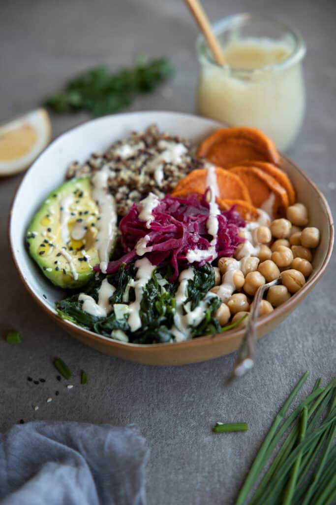 Quinoa Buddha bowl with tahini dressing drizzled over the top.
