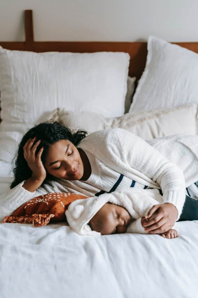 Mother and baby in bed snuggling while baby sleeps.