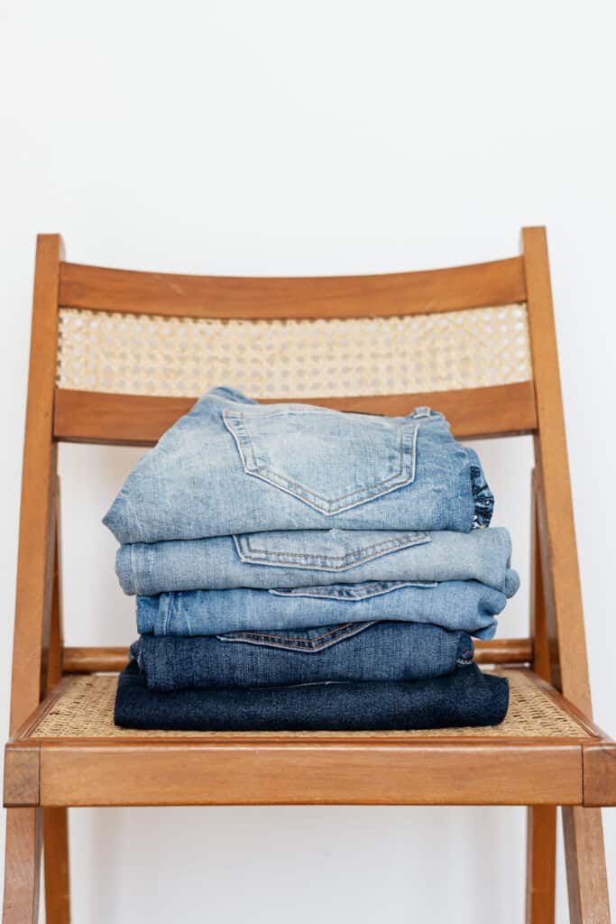 Pile of jeans on a chair.