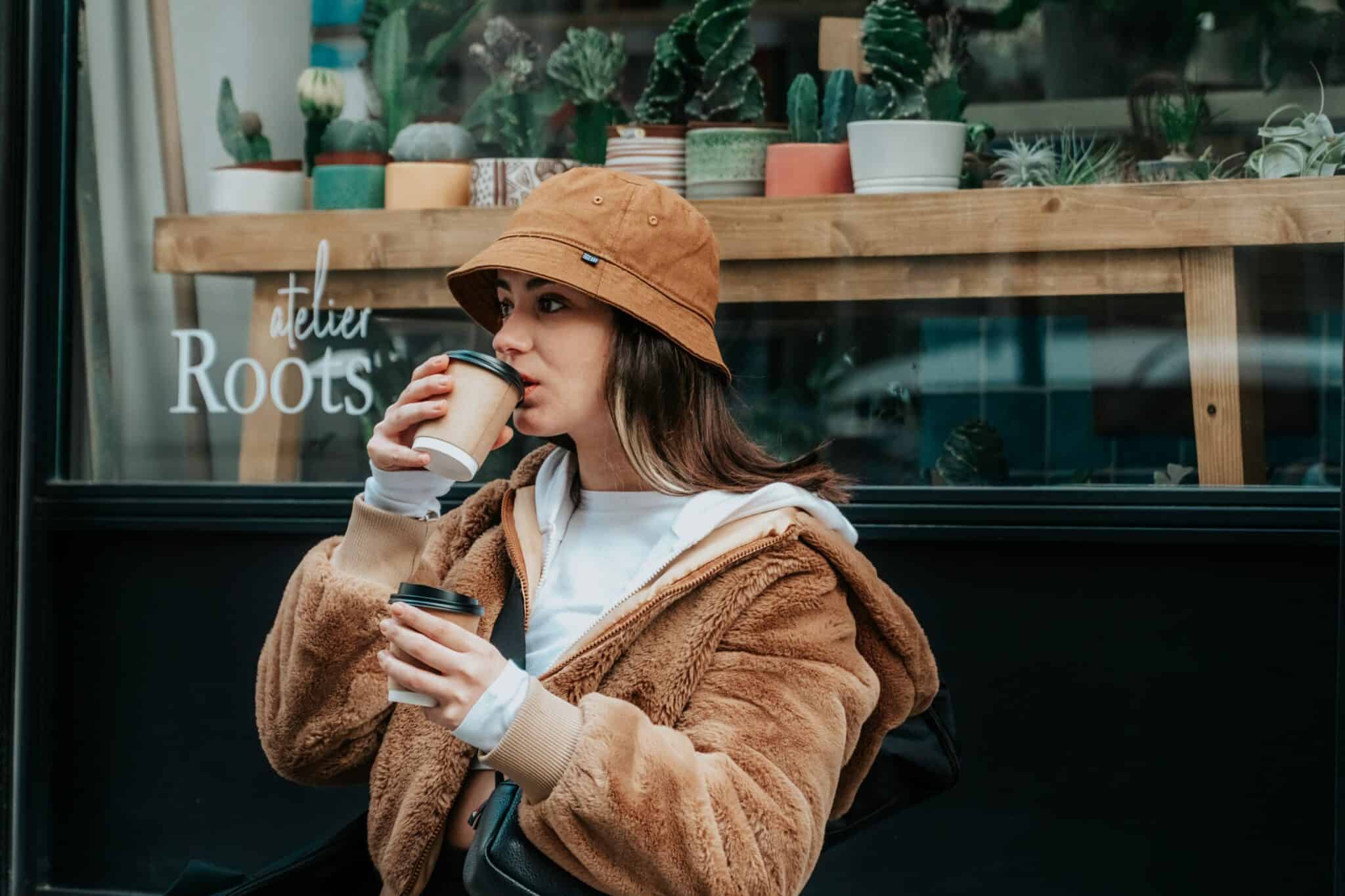 woman holding two takeaway coffees cups - an example of convenience culture