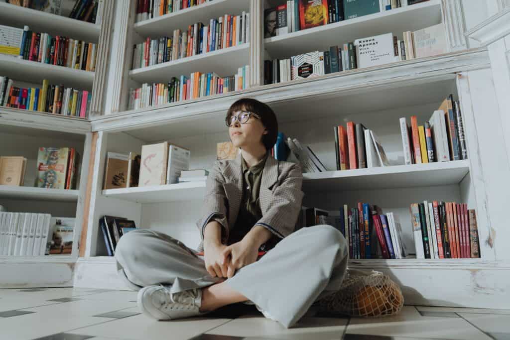 woman sitting on the floor of a library - an example of slow living